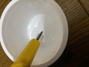 ヨーグルト容器に錐で穴を開けている様子