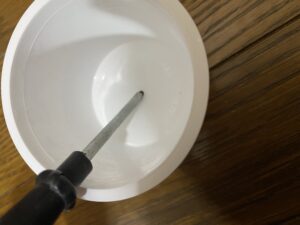 ヨーグルト容器の穴をドライバーで広げている様子